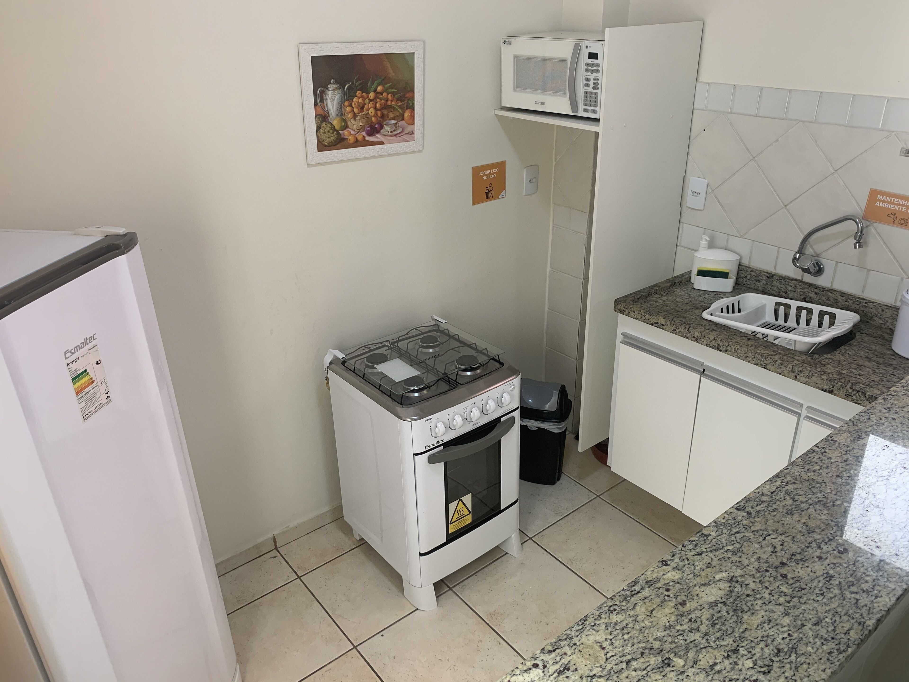 Cocina compacta con estufa a gas, microondas, lavaplatos y refrigerador.