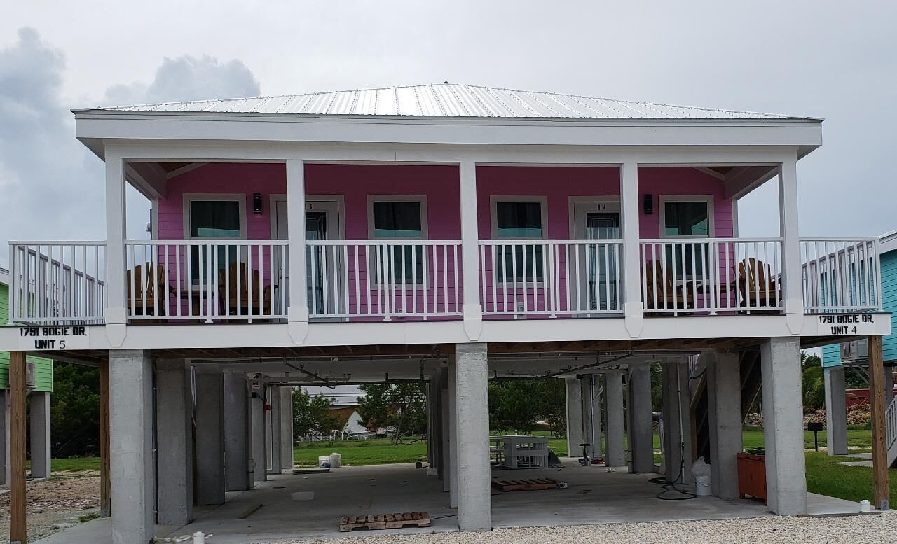 A two-story building with a balcony, concrete pillars, and a metal roof.