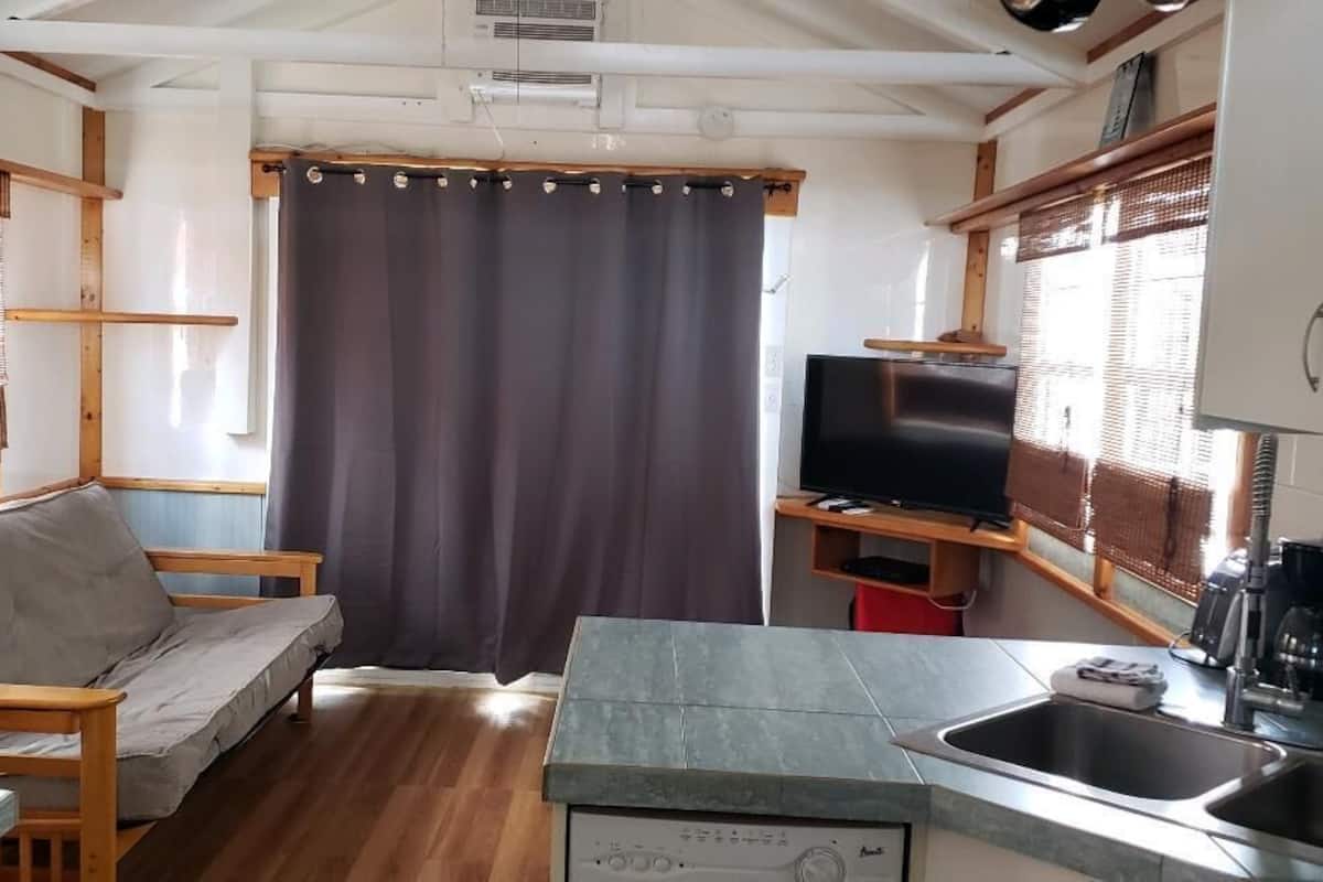 Een compact RV-interieur met een kitchenette, een zithoek met een bank en een televisie.