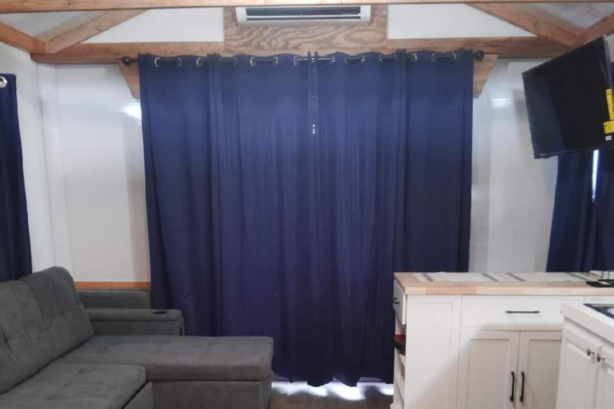 Een kamer met een hoekbank, een kast en een plafondventilator.