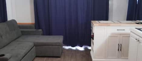 A room with a sectional sofa, a cabinet, and a ceiling fan.