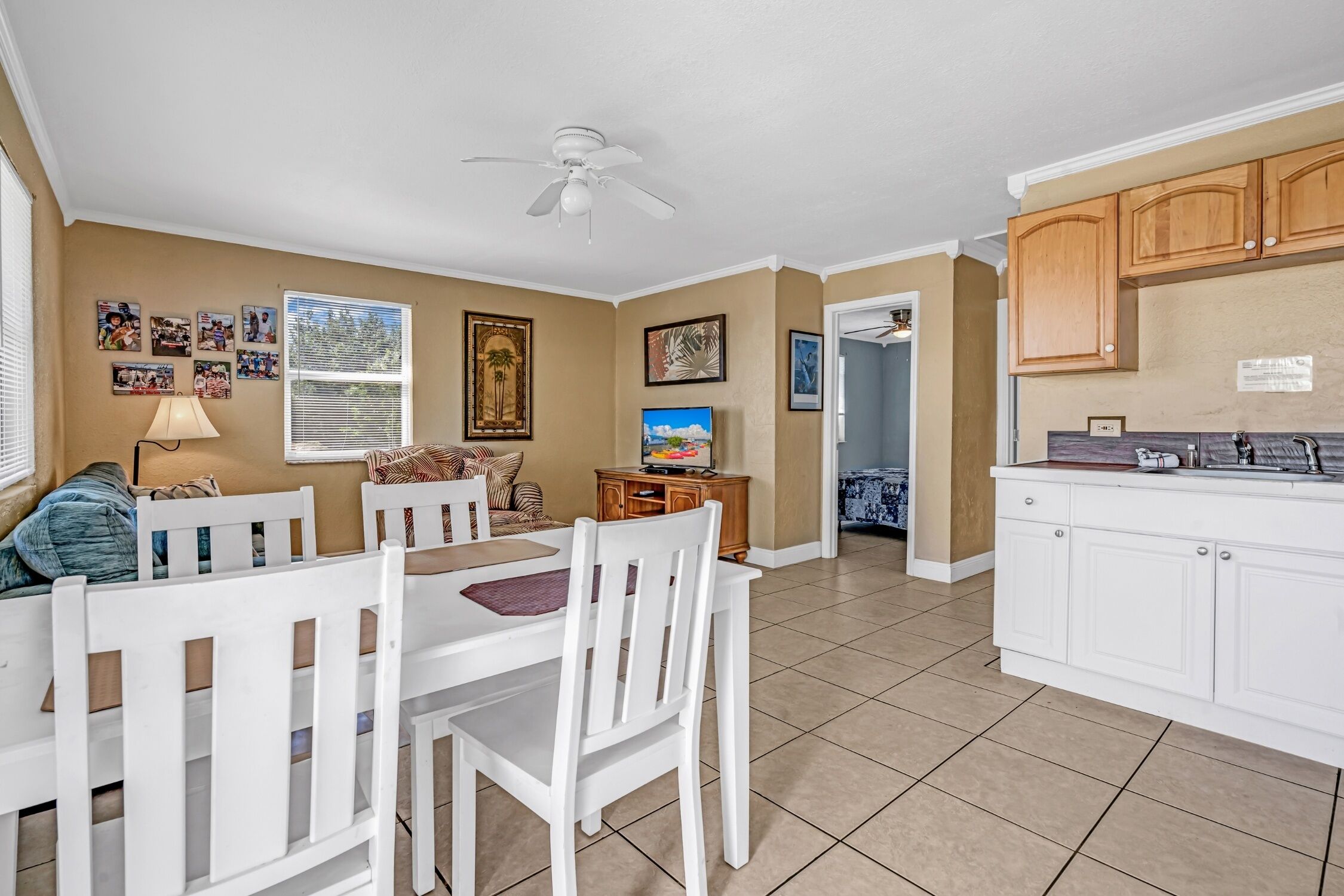 A spacious kitchen with white cabinets, a dining area with a table and chairs, and a ceiling fan.