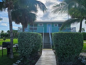 A pathway leading to a building with a blue exterior, surrounded by palm trees and hedges. - Old Wooden Bridge Resort and Marina (Big Pine Key)