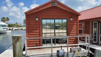 A red wooden building with a dock, a Yamaha outboard motor, and a clear view of the marina in the background.