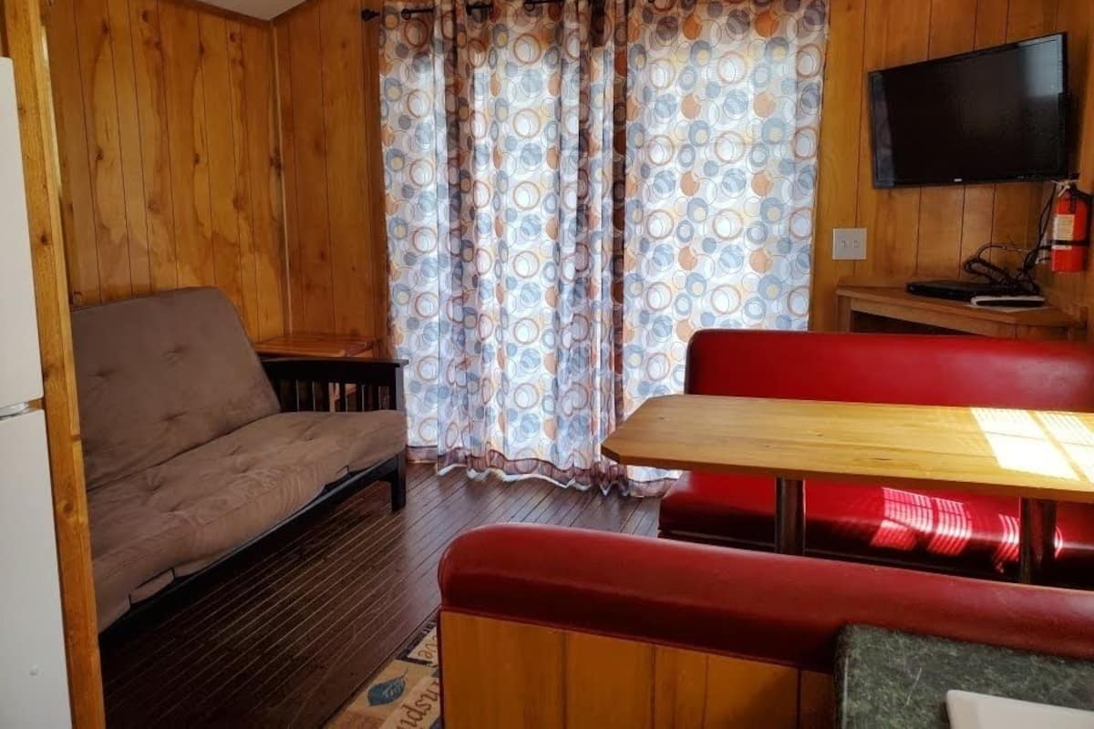 Een gezellig interieur van een blokhut met een bank, een houten tafel en een televisie.