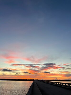 A bridge with a railing, leading to a body of water under a colorful sunset sky. - Old Wooden Bridge Resort and Marina (Big Pine Key)