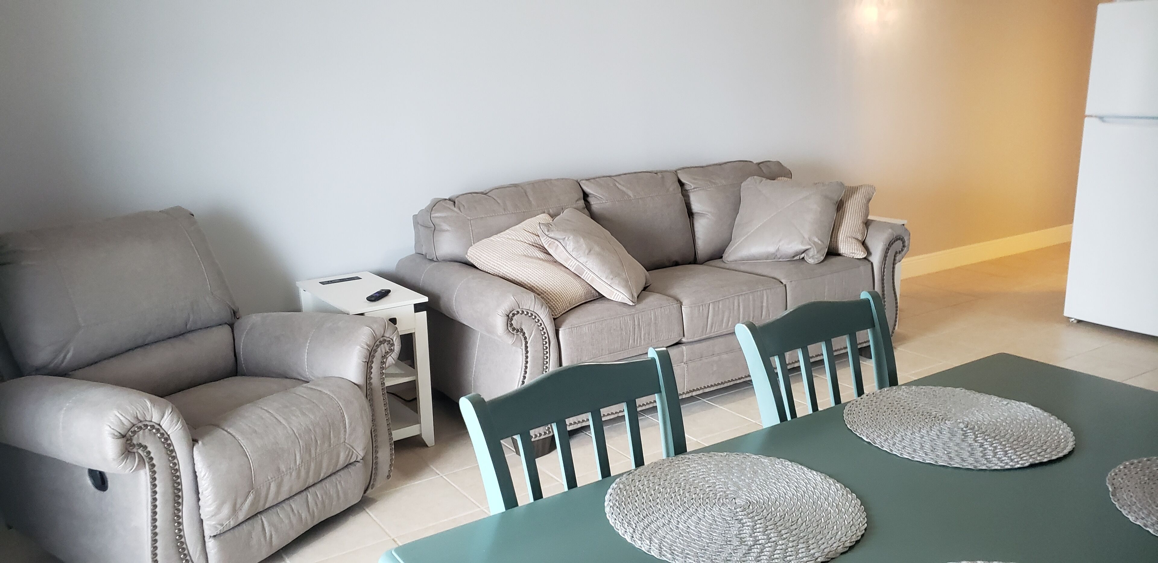 A living room with a sofa, a small side table, and a dining table with chairs.