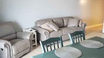 A living room with a sofa, a small side table, and a dining table with chairs.
