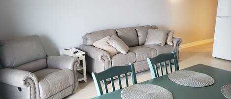 Un salon comprenant un canapé, une petite table d’appoint et une table à manger avec des chaises.