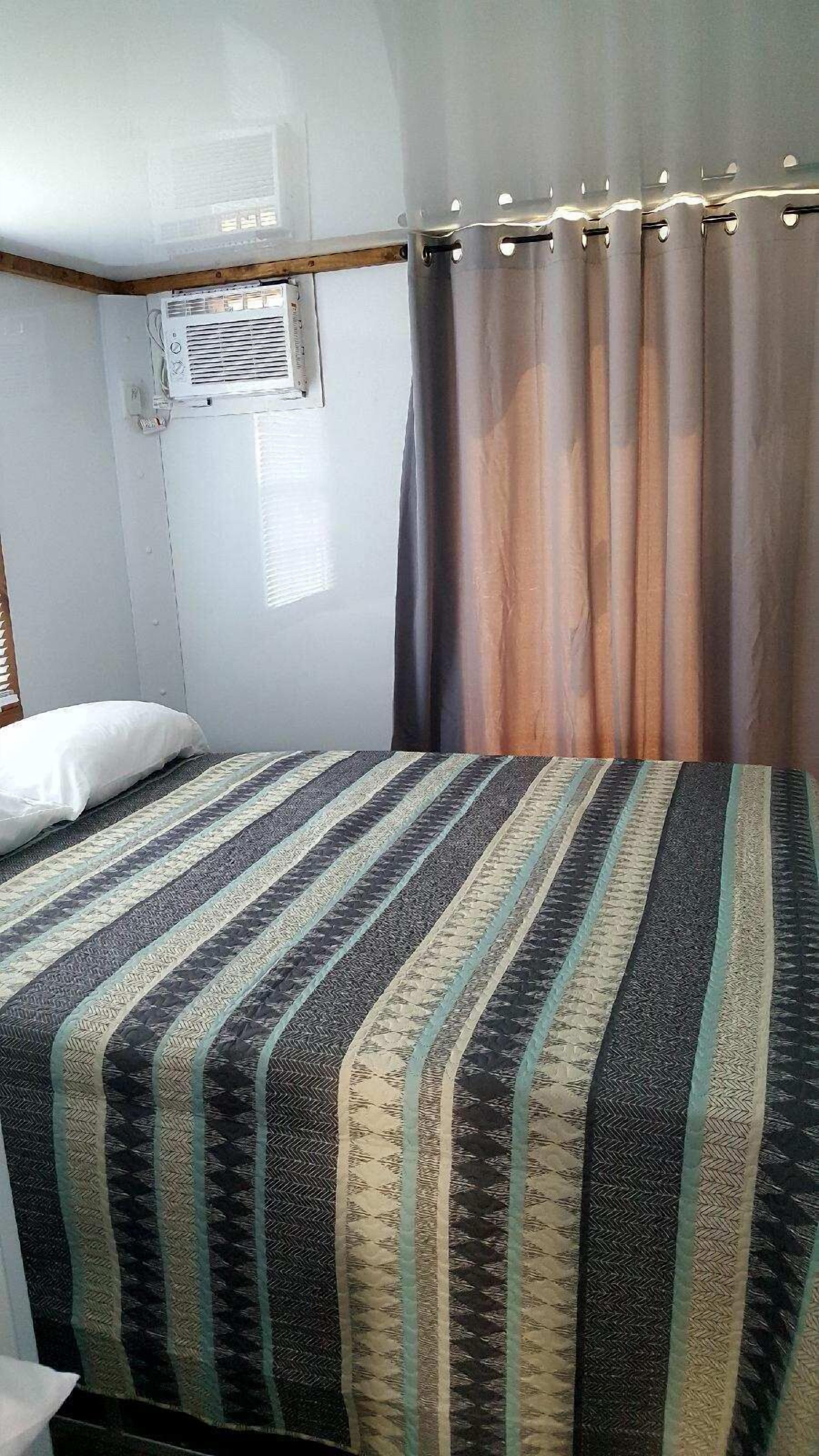 Een kamer met een bed, een raam met jaloezieën en een gordijn.