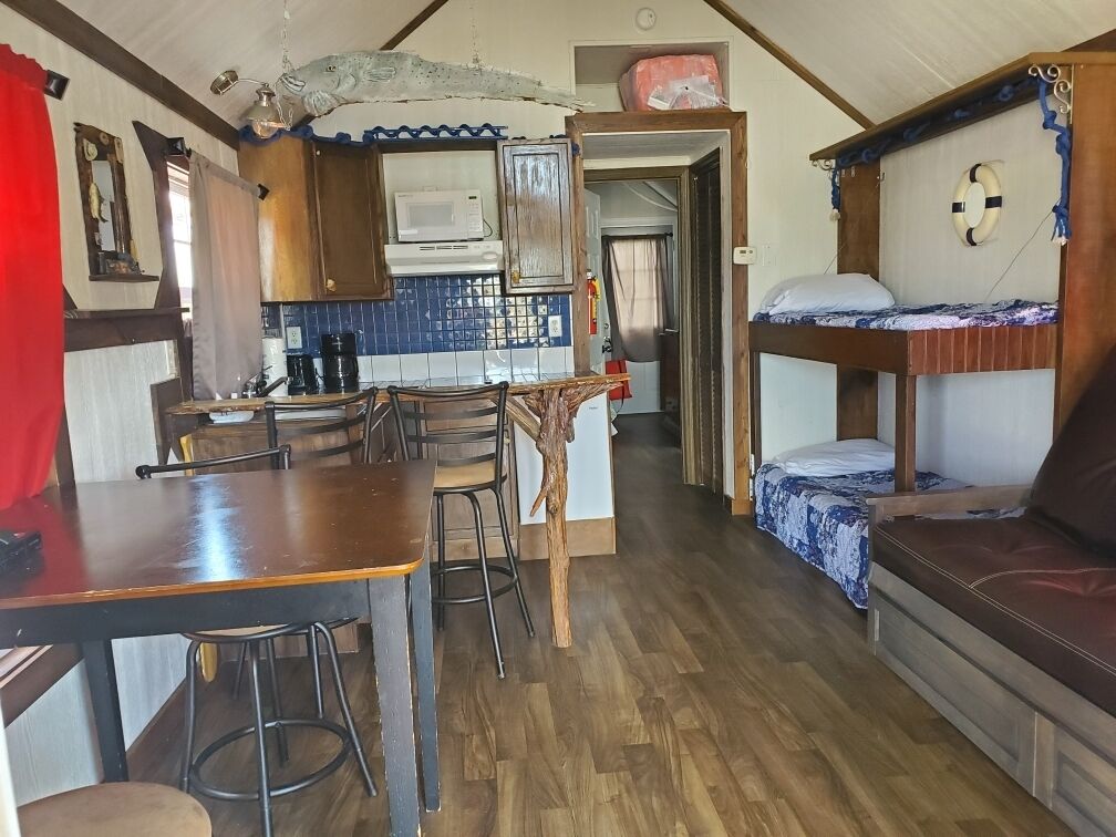 Una cabaña compacta con kitchenette, comedor y litera.