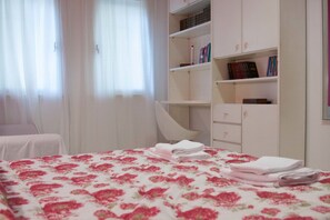 A bedroom with a bed, a chair, a wardrobe, and a desk. - Eva Holiday (Rome)