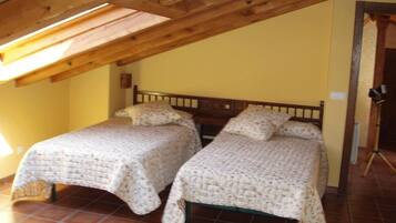 Una habitación con dos camas individuales, vigas de madera en el techo y suelo de baldosas.