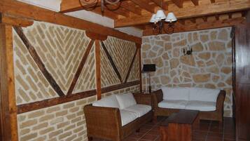 Una habitación acogedora con pared de piedra, vigas de madera y mobiliario de mimbre.