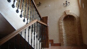 A staircase with a wooden handrail and black balusters, leading to a stone archway. - La Casona de Doña Petra (Villarmentero de Campos)