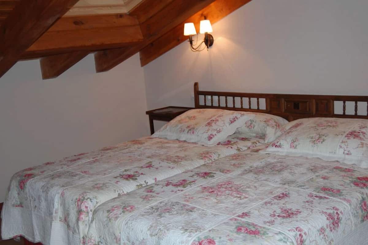 Une chambre à coucher avec un lit en bois, une literie à motifs floraux et une table de chevet.