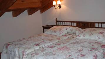 Un dormitorio con estructura de cama de madera, ropa de cama floral y una mesita de noche.