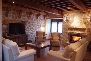 Un salón acogedor con paredes de piedra, chimenea y asientos cómodos.