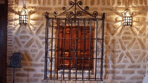 A stone wall with a metal gate and two wall-mounted lanterns. - La Casona de Doña Petra (Villarmentero de Campos)