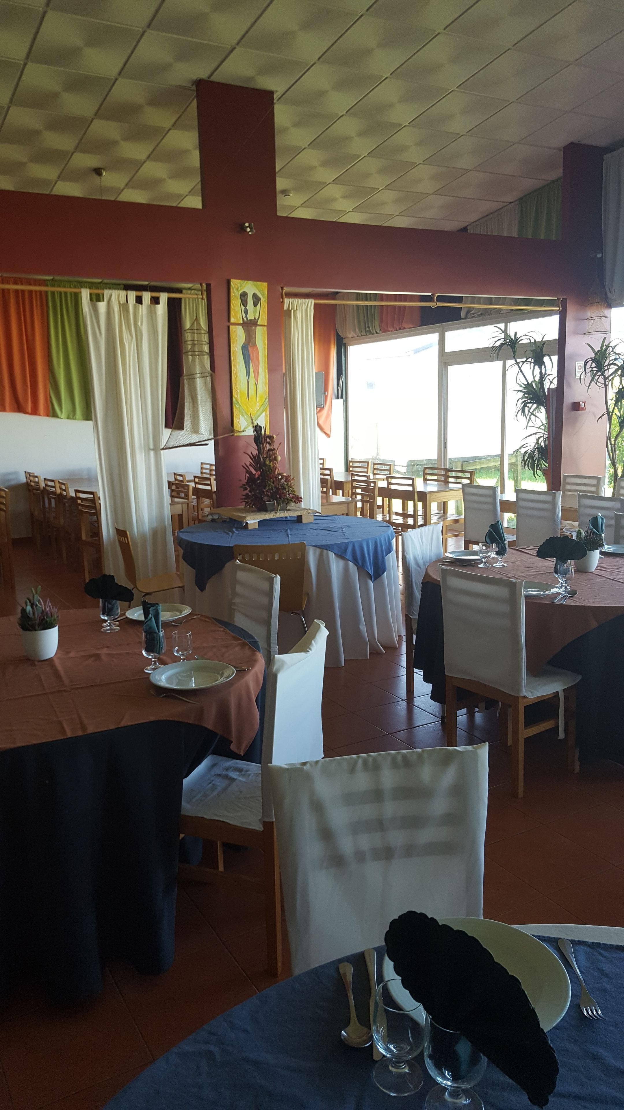 Een restaurant met verschillende tafels klaar voor diners, met een verscheidenheid aan stoelen en een plafond met een rasterpatroon.