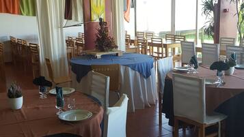 Een restaurant met verschillende tafels klaar voor diners, met een verscheidenheid aan stoelen en een plafond met een rasterpatroon.