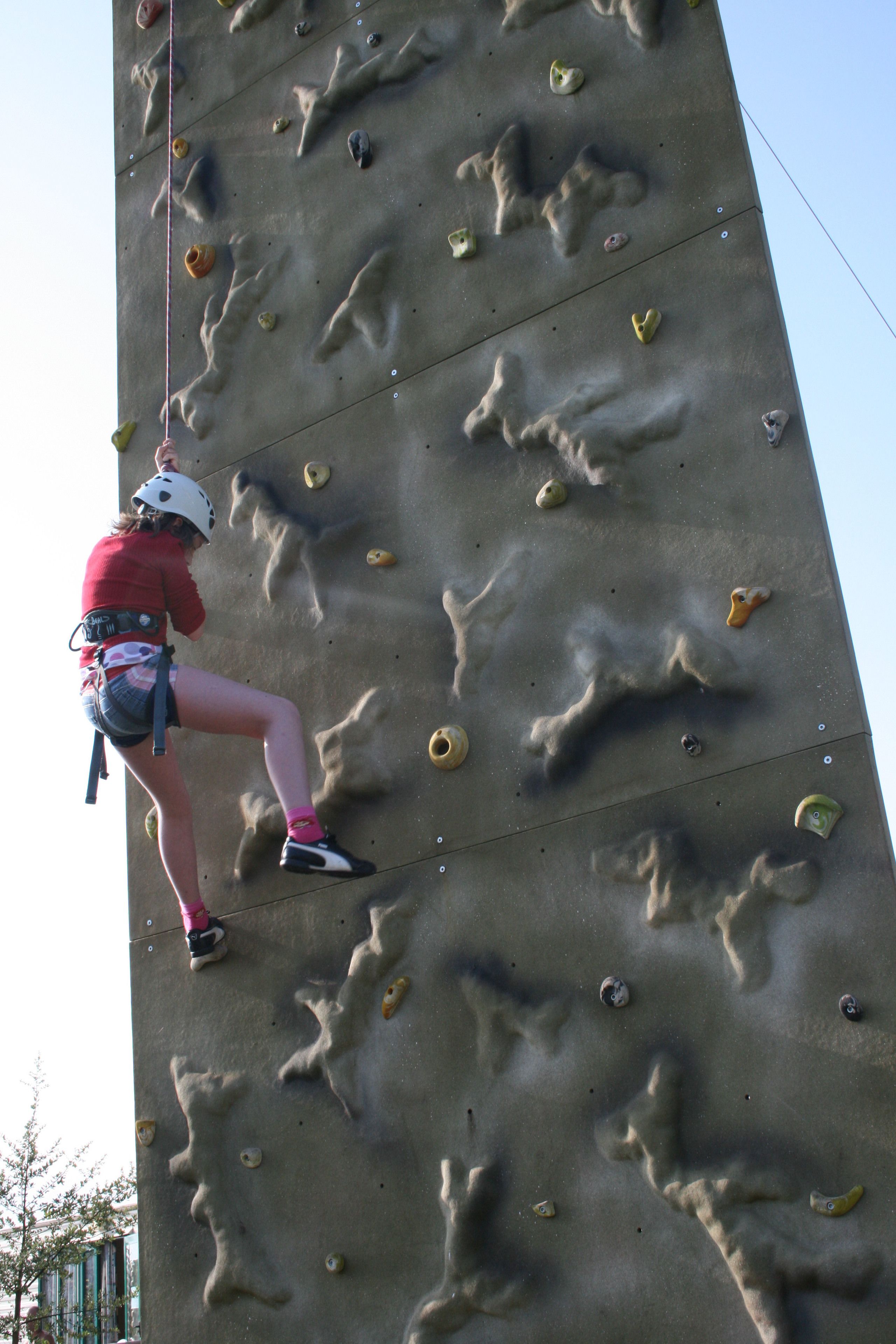 A person climbing a rock wall with handholds and footholds.