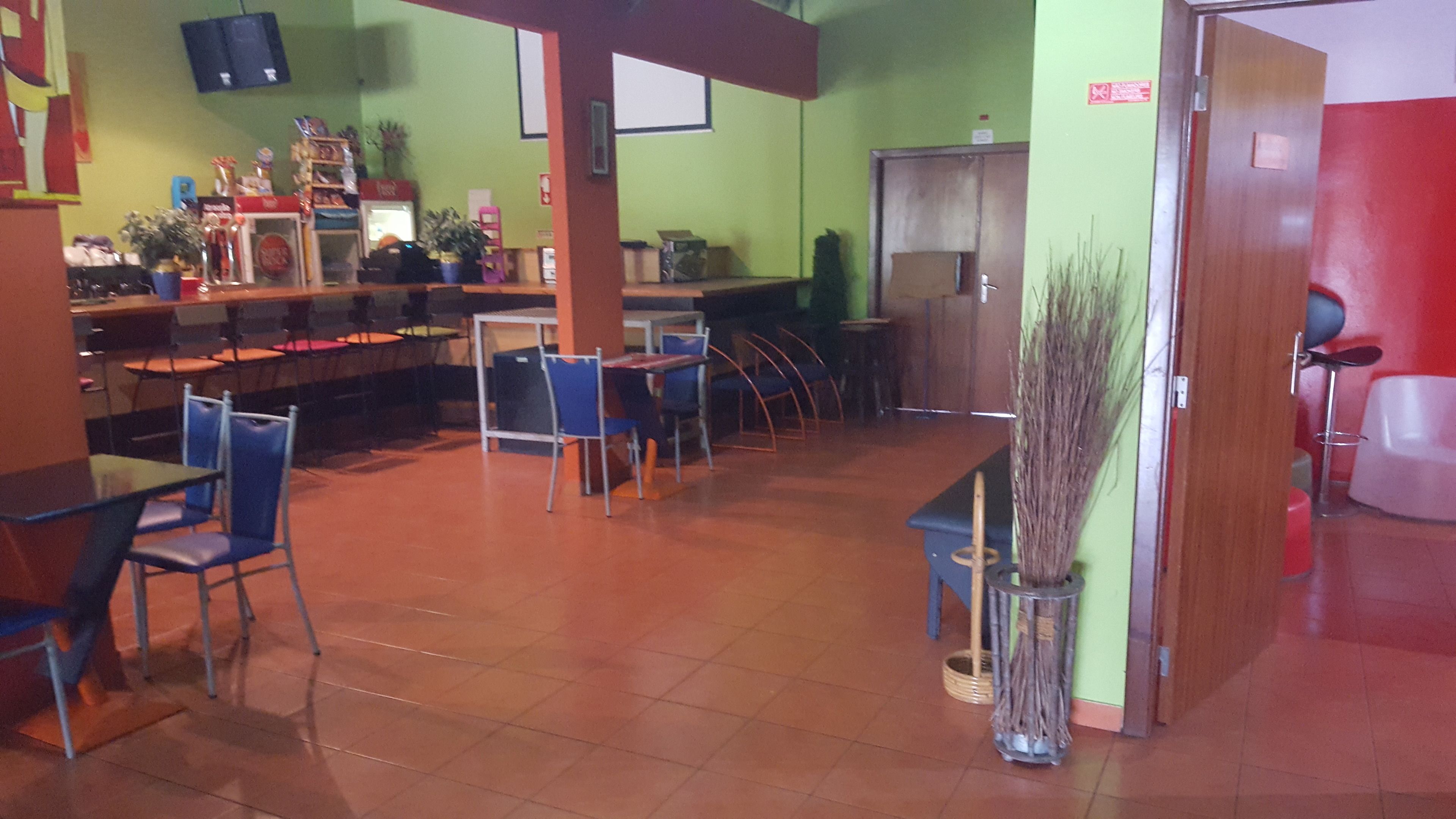 Un restaurante con varias mesas y sillas, una barra y algunas plantas.