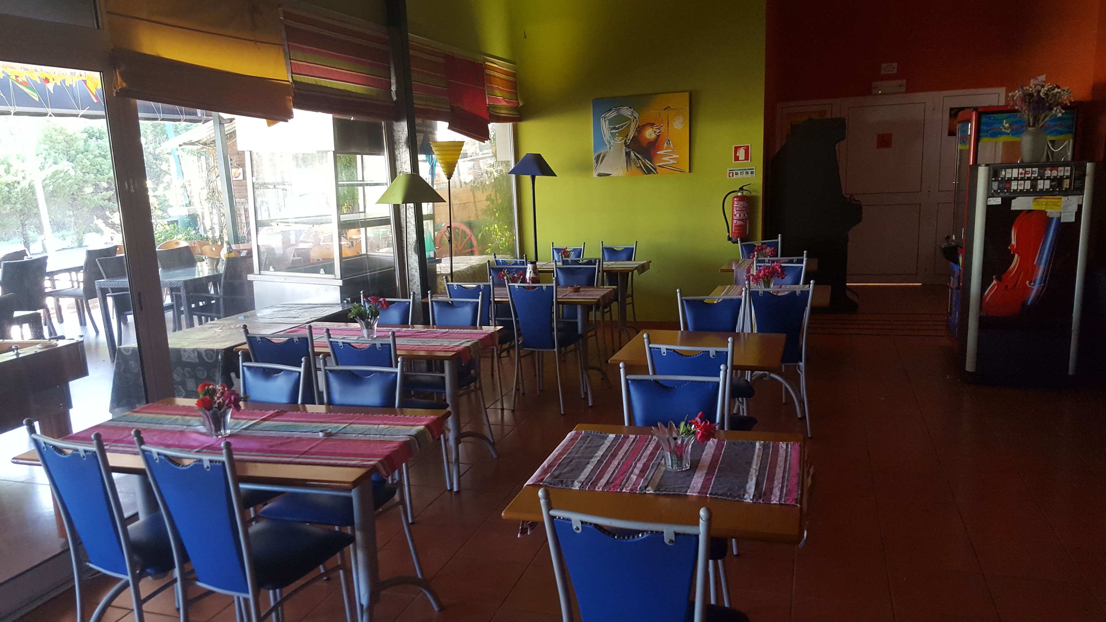 A restaurant with tables and chairs arranged in rows, a fire extinguisher on the wall, and a door in the background.