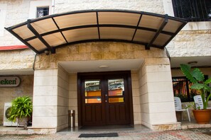 Ein Hotel mit hölzernen Doppeltüren, einem überdachten Eingangsbereich und einem Blumentopf auf der rechten Seite.