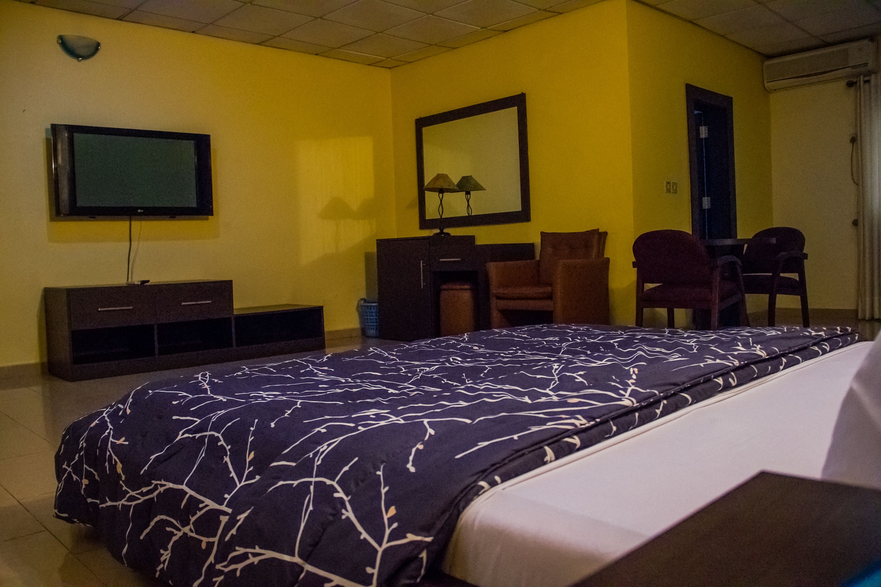 A hotel room with a bed, a desk, a chair, a television, and a mirror.
