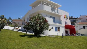 Un edificio moderno de dos pisos con techo plano, balcón y toldo rojo.