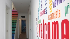 Un pasillo con una pared colorida y un cartel con los números de las habitaciones.