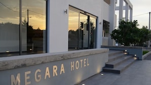 The exterior of the Megara Hotel with a modern design, featuring large glass windows and a prominent entrance with steps leading up to the door. - Megara Hotel (Megara)