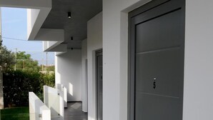A modern building with a long corridor, a grey door with a number, and a small window. - Megara Hotel (Megara)