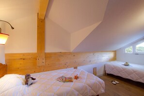 A bedroom with two beds, wooden headboard, a window, and a lamp. - Apartment in French Alps for All Group Sizes (Les Deux Alpes)