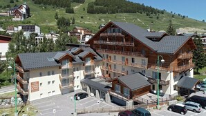 Un hotel de varios pisos con balcones y una zona de estacionamiento.