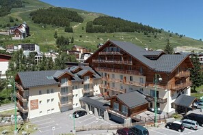 A multi-story hotel with balconies and a parking area. - Apartment in French Alps for All Group Sizes (Les Deux Alpes)
