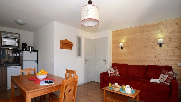 Un espacio habitable compacto con comedor, un sofá rojo y una kitchenette.