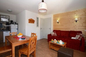 A compact living space with a dining area, a red sofa, and a kitchenette.