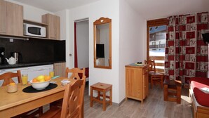 Cocina compacta con microondas, estufa y comedor con mesa para dos.