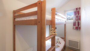 Habitación con literas, una ventana, un radiador y un peluche en la cama inferior.