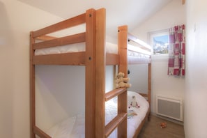 A bunk bed room with a window, a radiator, and a stuffed toy on the lower bunk. - Apartment in French Alps for All Group Sizes (Les Deux Alpes)