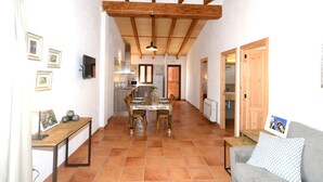 A spacious kitchen with a dining area, wooden ceiling beams, and a tiled floor. - Agroturismo Can Porretí (Lloret de Vistalegre)