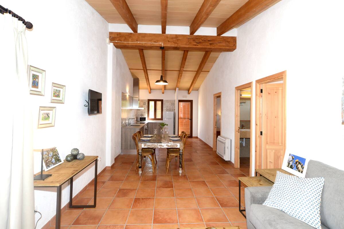 A spacious kitchen with a dining area, wooden ceiling beams, and a tiled floor.