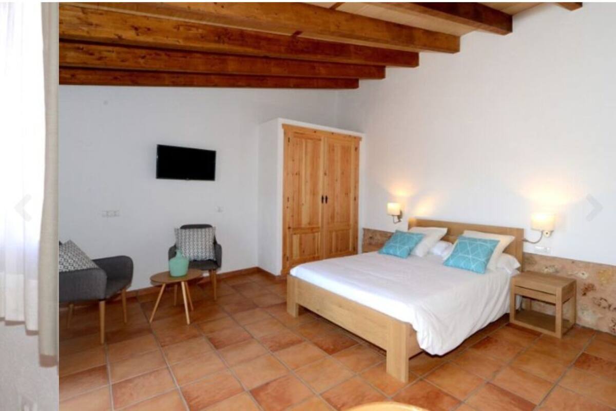 A bedroom with a wooden bed, a wardrobe, a small table, and a chair.