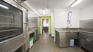 A commercial kitchen with stainless steel appliances, a sink, and a water fountain. - El Albergue de la Catedral - Hostel (Vitoria-Gasteiz)