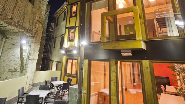 A multi-story building with a ground-level restaurant featuring outdoor seating. - El Albergue de la Catedral - Hostel (Vitoria-Gasteiz)