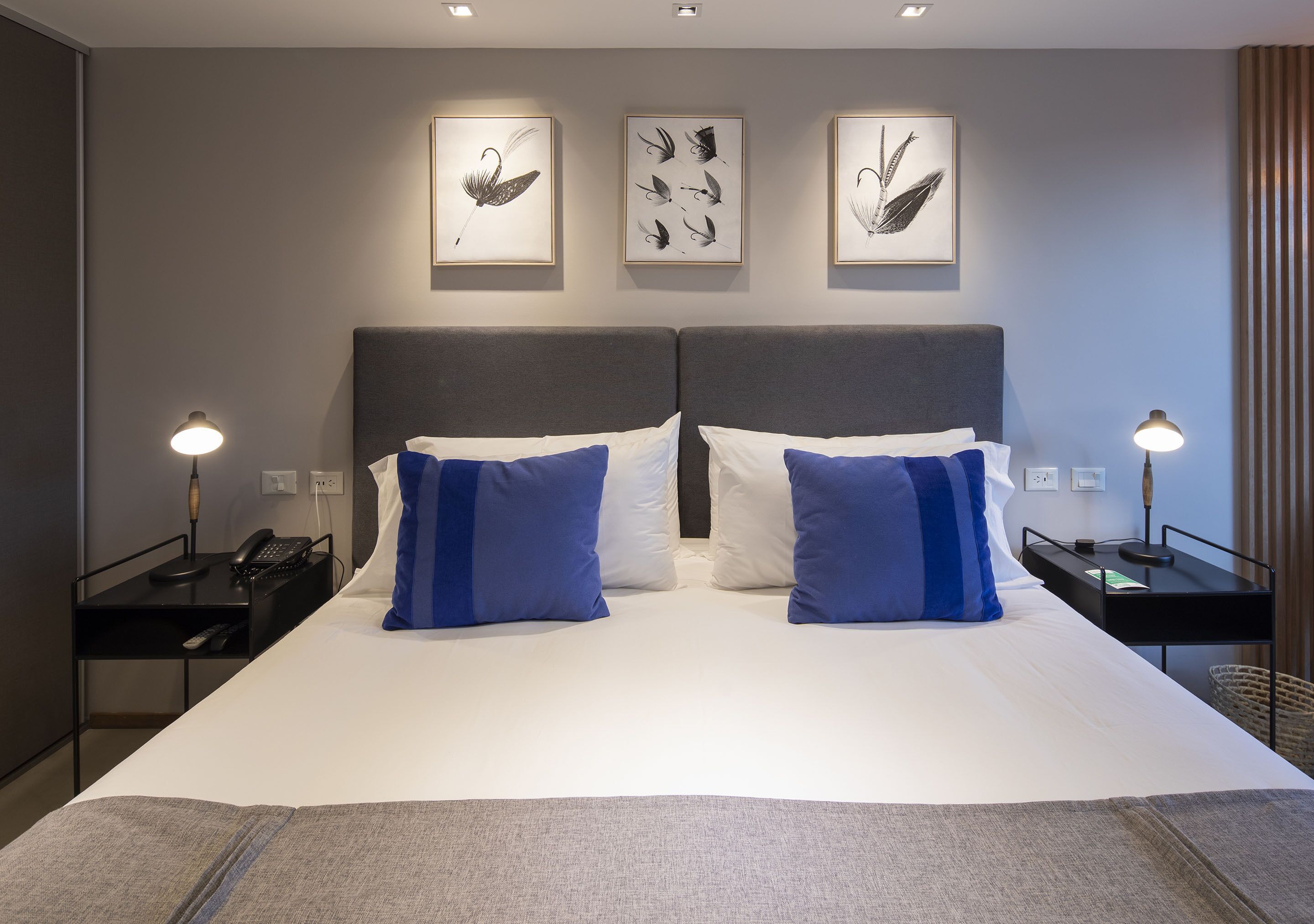 Una habitación de hotel con una cama grande, dos mesitas de noche y tres obras de arte colgadas en la pared.