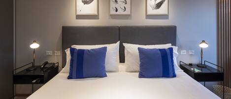 Una habitación de hotel con una cama grande, dos mesitas de noche y tres obras de arte colgadas en la pared.