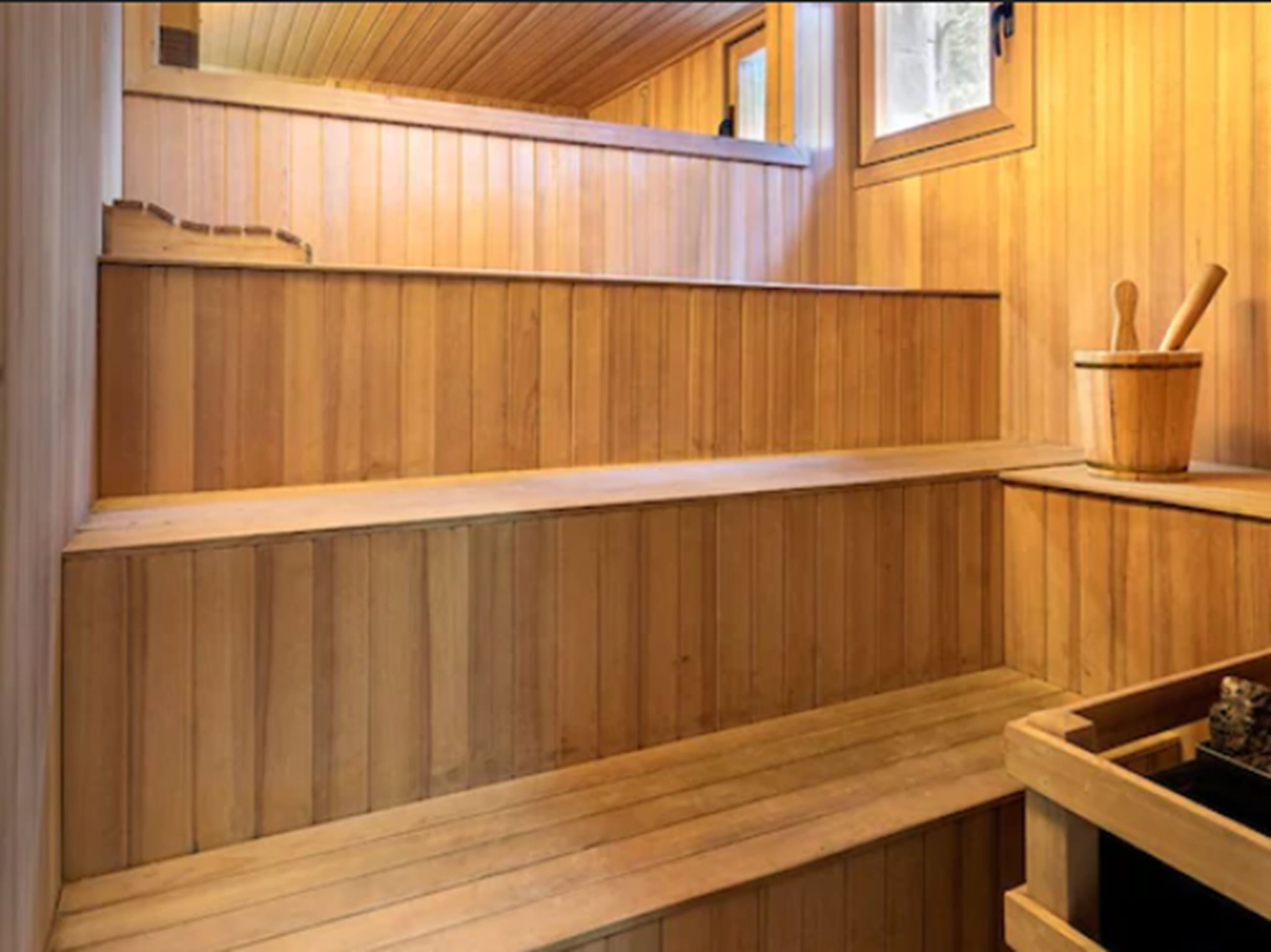 A wooden sauna with benches and a wooden bucket with a brush.